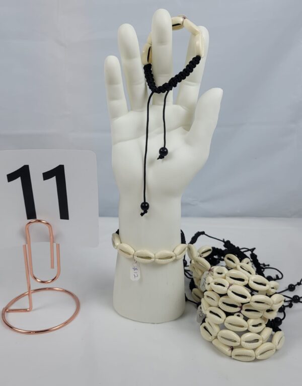 Plastic shells/cowries, woven with black thread to create this beautiful bracelet, its adjustable to fit every hands